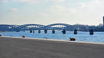 Bridge over river with cloudy sky.