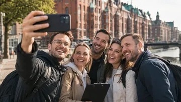 Group taking selfie by canal, old buildings.
