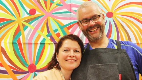 Two people smiling, colorful abstract background.