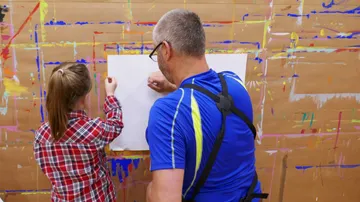 Mann und Kind zeichnen an Papierwand.