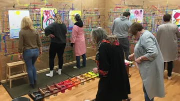 People painting on canvases indoors workshop.