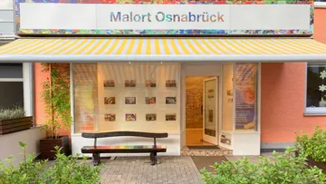 Art gallery facade with bench outside.