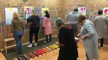 Personen malen an Wänden im Kunstkurs.