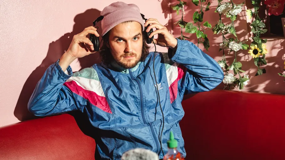 Man wearing headphones seated on red couch.