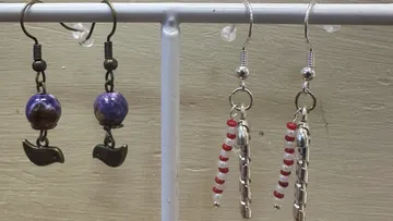 Two pairs of handmade earrings hanging on a stand.
