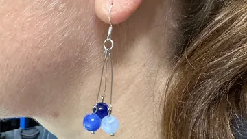 Earring with blue beads on woman's ear.