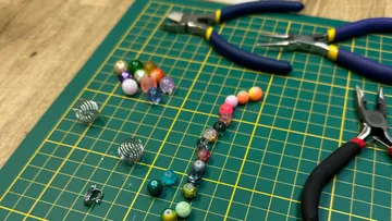 Tools and beads on a green grid mat.
