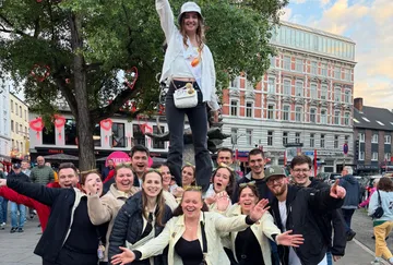 Gruppe feiert draußen, eine Person erhöht.