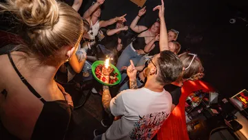 Personen feiern in einem dunklen Raum.