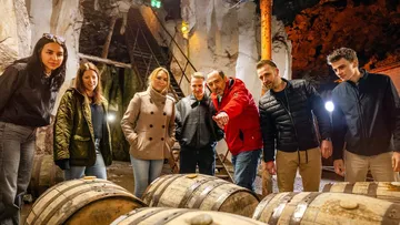 People examining wooden barrels in a cave.