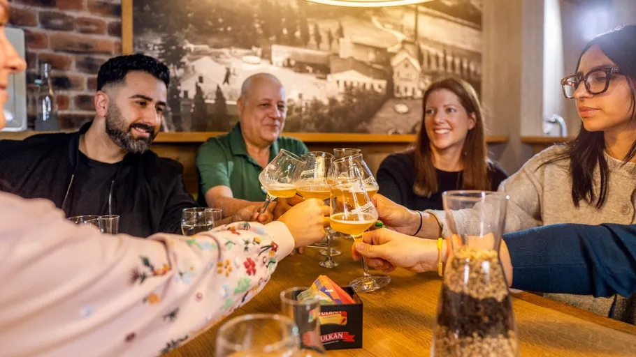 Friends toasting with beer glasses indoors.