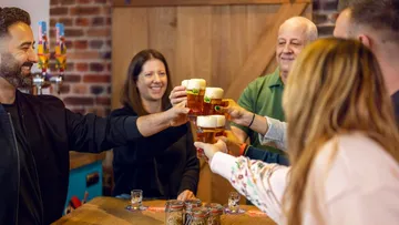 People toasting with beer in a bar.