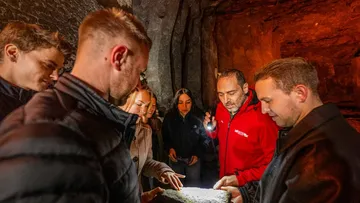 Group examining rock in dimly lit cave.