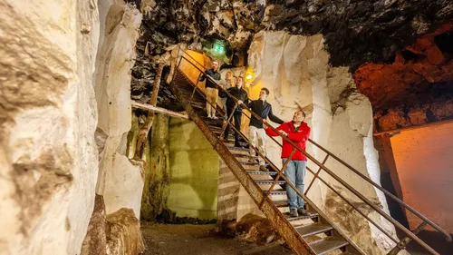 People ascending stairs inside a rocky cave.