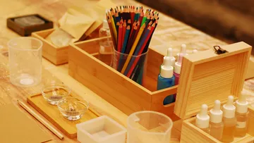 Colored pencils in a wooden box on table.