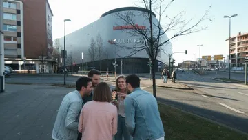 Menschen versammelt, schauen Handy vor Einkaufszentrum.