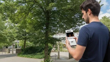Mann hält Handy, geht im Park.