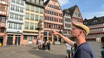 Mann zeigt auf historischem Stadtplatz.