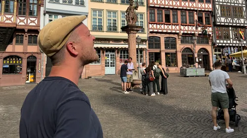 Mann lächelt auf sonnigem historischem Platz.
