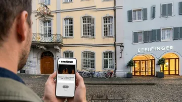 Person holds phone with app outside building.