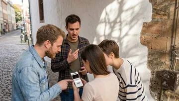 Group checking phone outside on street.