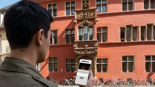 Person benutzt Smartphone vor Gebäude.