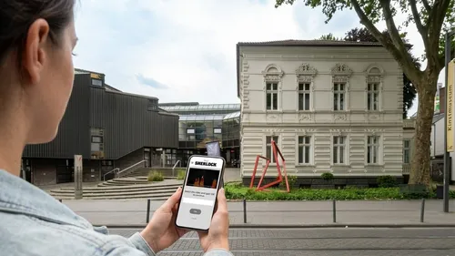 Person holding phone in front of museum.