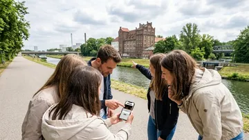 Gruppe schaut auf Smartphone am Fluss.