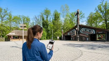 Person nutzt Smartphone nahe Totem-Ausstellung.