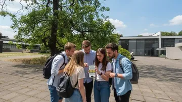Group of students looking at a phone outdoors.