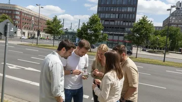 Gruppe betrachtet Handy, städtische Straßenszene.