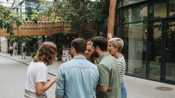 Group gathering to view phone outdoors.