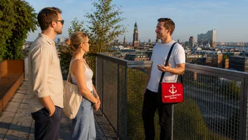 Drei Personen sprechen auf einer Dachterrasse.