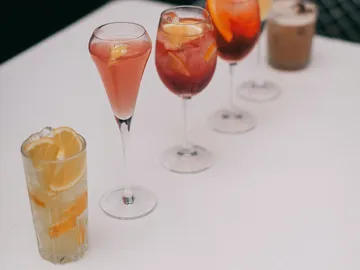Fünf bunte Cocktails stehen auf einem Tisch.