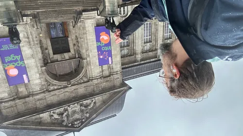 Man walking past a historic building.
