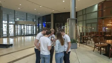 Gruppe versammelt sich um Handy in Lobby.