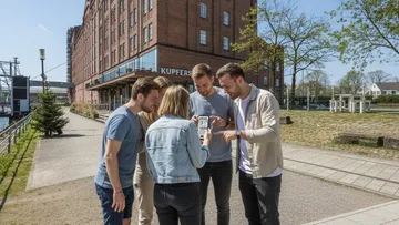 People examining phones in urban park.