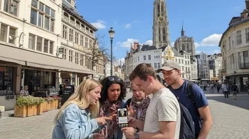 Gruppe von Personen schaut auf Handy im Stadtplatz.