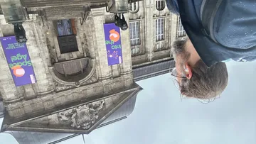Person bewundert großes Gebäude mit Bannern draußen.