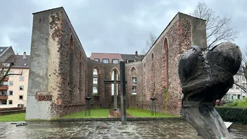 Ruinen einer Kirche mit Skulptur davor.
