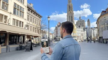 Mann hält Handy auf Stadtstraße.