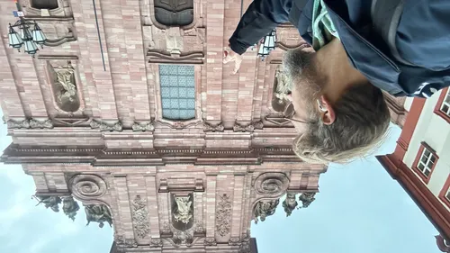 Mann zeigt auf historische, verzierte Gebäude Fassade.