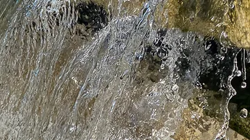 Water flows over rocky surfaces outdoors.