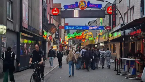 Menschen gehen auf einer Neonbeleuchteten Straße.