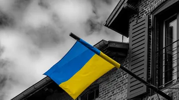 Ukrainian flag flying outside brick building.