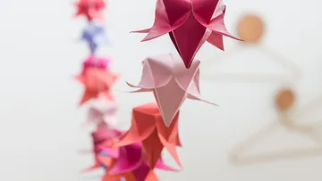 Origami-Formen hängen in einem unscharfen Raum.