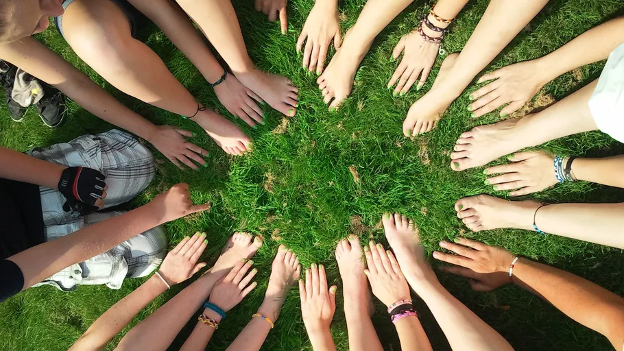 Hands and feet forming circle on grass.