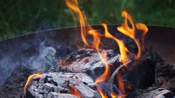Lagerfeuer brennt mit Holzscheiten im Freien.