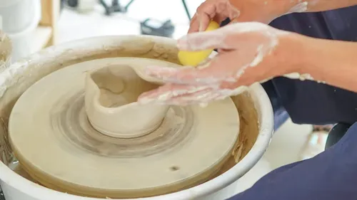 Person shaping clay on pottery wheel.