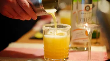 Hand pouring cocktail into a glass.